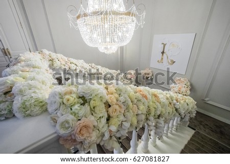 Beige and white flowers stand before picture with letter K on the wall