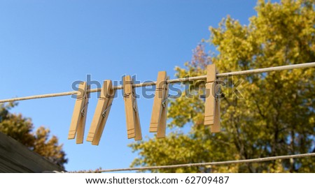 Clothespins hanging on the line with blue sky and trees with copy space