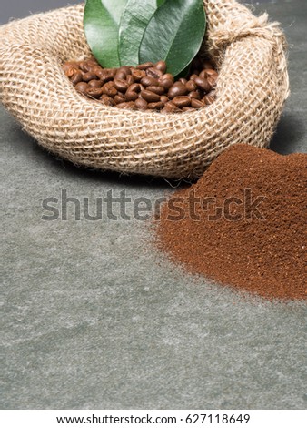 Coffee sack with roasted beans and pile of grounded coffee over dark gray granite plate