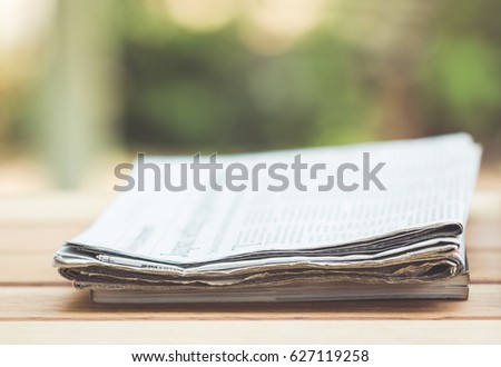 Daily newspaper on the wooden table with nature abstract background.