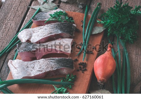 Sliced fresh fish with spices and parsley on a wooden board