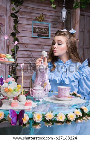 Alice sitting at the tea table and eating a cookie