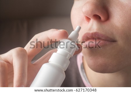 A woman with a runny nose holds a medicine in her hand, a red nose Royalty-Free Stock Photo #627170348