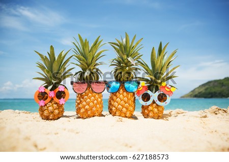 Family of funny attractive pineapples in stylish sunglasses on the sand against turquoise sea. Tropical summer vacation concept. Happy sunny day on the beach of tropical island. Family holiday Royalty-Free Stock Photo #627188573