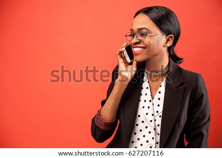 Happy afroamerican businesswoman talking on the phone on the red background.