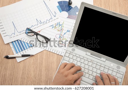 Man's hand typing on laptop computer. Business report, business summary laid on desk.  Business work at home office. Business concept.
