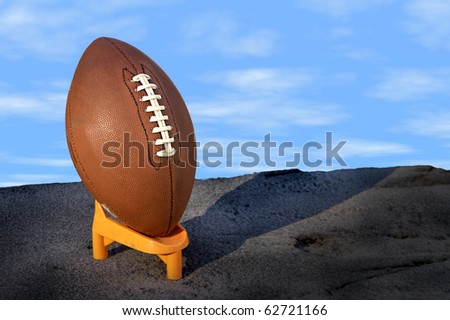 Football on a tee with blue background clouds and copy space