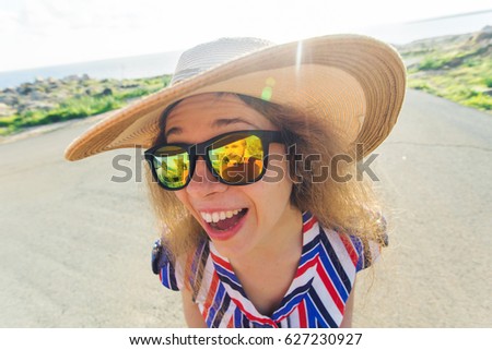 Summer, holiday, selfie and vacation concept - Young woman making funny face at summer day wearing hat and sunglasses