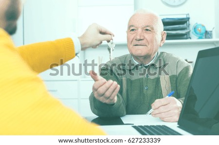 Pensioner and lease agent sign lease contract of apartment at office and hand over keys