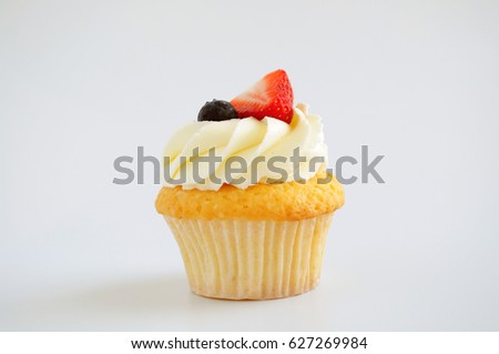 Cupcake with whipped cream, fresh strawberry, blueberry on white background. Isolated. Picture for a menu or a confectionery catalog.