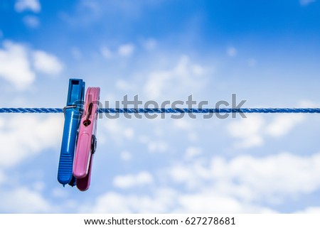 Blue and red clothespins on a clothes line in front of a blue sky