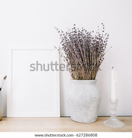 Front view blank mock up of photo frame with lavender bouquet and trendy stuff at white background. Minimalistic decorated home office concept.