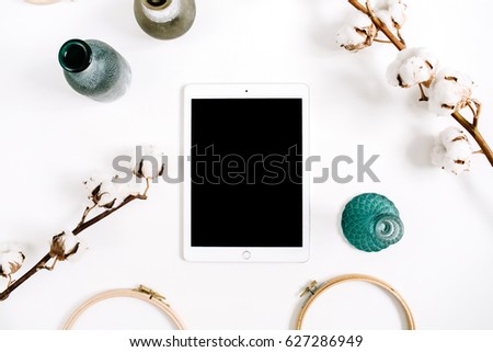 Blogger or freelancer workspace with blank screen tablet and cotton at white background. Flat lay, top view minimalistic decorated home office desk.