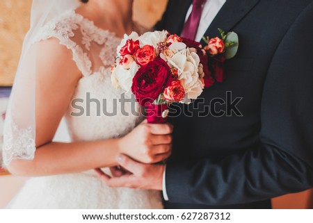 Beautiful wedding bouquet of flowers in hands of the bride and groom