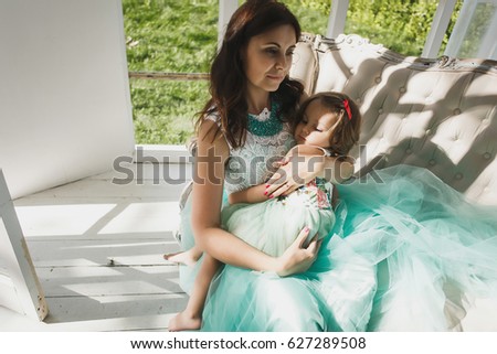 Happy mother hugging her adorable little daughter. Happy loving family.  Summer terrace.   little girl sleeping in mom hands. 
