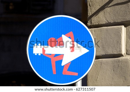Road sign with a man playing guitar on the signal, street art, metropolitan