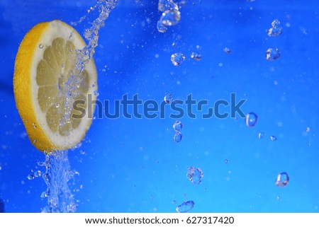 slice of lemon in the water with bubbles, on blue background
