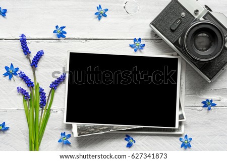 vintage retro camera, blank photo frame and spring blue flowers bouquet on white wooden background. mock up. top view. sprig concept