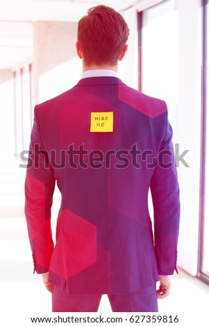 Rear view of young businessman with hire me adhesive note at office