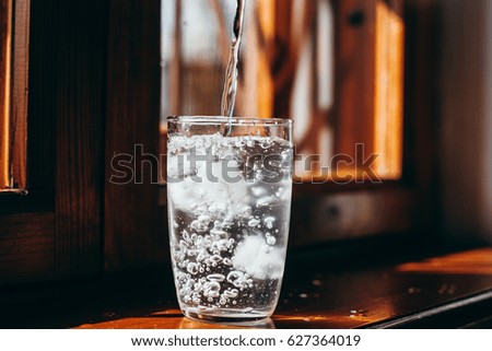 water is poured into a glass with ice