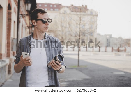 Young hipster man walking on the street and using his smartphone. With copy space