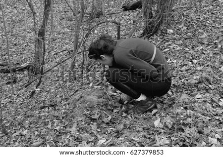 Black and white picture of a young girl looking at oak leaves in the wilderness