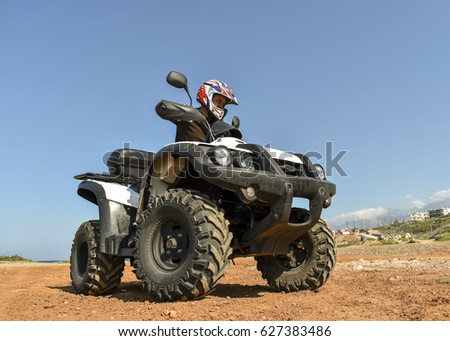 A man riding ATV in sand in protective  helmet.
