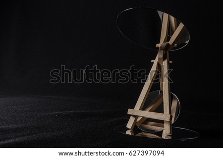 Empty miniature easel abstract composition with mirrors isolated on black background. Copy space or room for text. Concept or metaphor for creativity, ideas, success, reflection, study