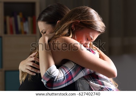 Side view of two sad good friends embracing in a bedroom in a house interior with a dark light in the background Royalty-Free Stock Photo #627402740