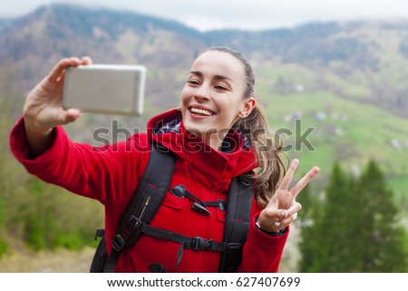 Happy woman hiker with backpack doing selfie on the phone while wolking in mountain. Perfect nature.