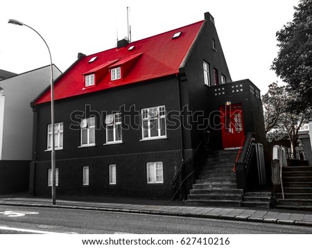 Facade of a black house with a vibrant red roof and doors in the old town of Reykjavík, Iceland. Exterior view of a Nordic downtown neighborhood building. Traditional Icelandic architecture. Royalty-Free Stock Photo #627410216
