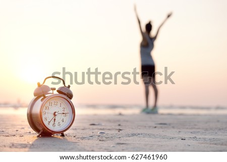 Morning of a new day, alarm clock  woman playing yoga and stretching muscles on the beach sunlight in morning. Health concept. Royalty-Free Stock Photo #627461960