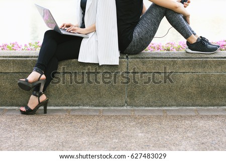 Business woman working on the laptop computer sitting near the relaxing sport woman in city park, Life balance concept, Workaholic and healthy lifestyle. Royalty-Free Stock Photo #627483029