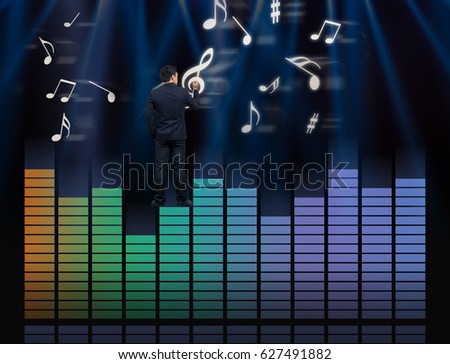 Businessman standing over the sound waves equalizer and drawing the  music note on dark background,musical concept