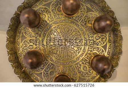 Top view of an ornamental golden tray with an intricate arabic design. Close up of tea tray with its details.