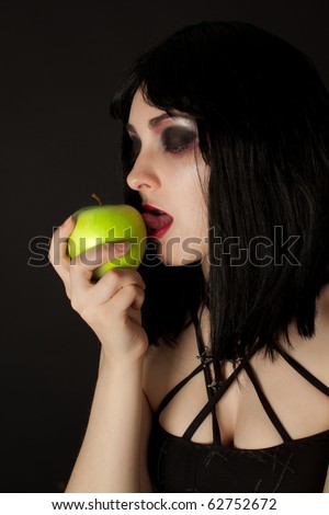 Picture of woman with halloweeen make up licking green apple