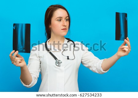 Young female doctor looking at the x-ray picture on blue background