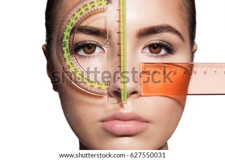The woman's face is measured with colored rulers before the plastic surgery to change the proportions. Isolated on white background Royalty-Free Stock Photo #627550031