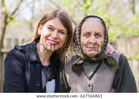 Picture of a sick elderly woman posing with her happy caretaker outdoor