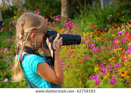 young girl taking photos by professional digital camera in autumn garden