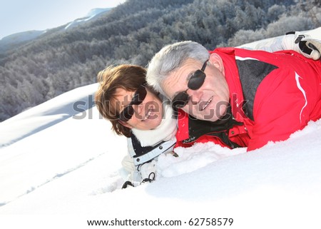 Portrait of a senior man and a senior woman laid in snow