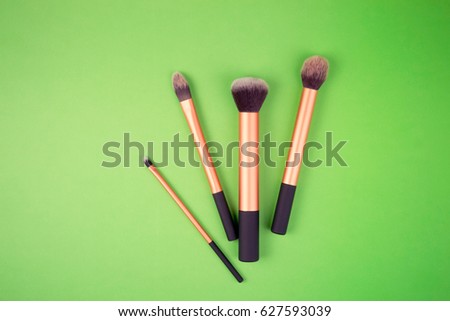 Make up brushes on greenery background. Top view.