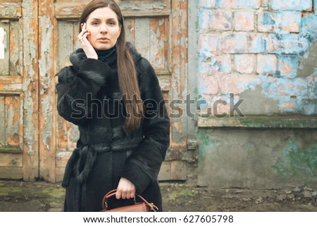  Photo shoot of the girl, in the city, against the background of buildings, and a brick fence.