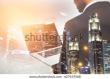 Business Concept Photo of businessman holding Laptop. Double exposure photo  view of the  night city . soft focus