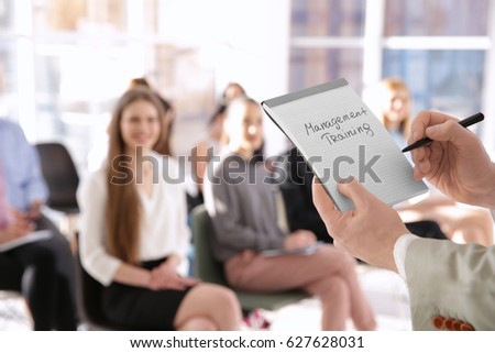 Business trainer holding notebook with text MANAGEMENT TRAINING at presentation Royalty-Free Stock Photo #627628031