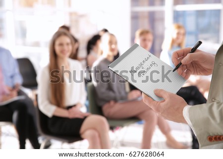 Business trainer holding notebook with text MANAGEMENT TRAINING at presentation Royalty-Free Stock Photo #627628064