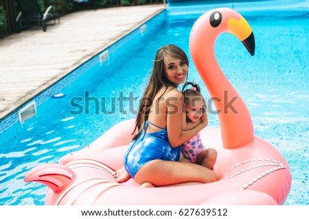 pregnant mother and her daughter was floating on an inflatable pink flamingos