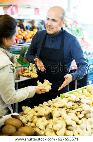 Portrait of smiling senior man selling ginger to female adult customer