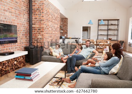 Family Sit On Sofa In Open Plan Lounge Watching Television Royalty-Free Stock Photo #627662780