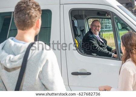 Smiling professional driver in van looking at passengers at airport Royalty-Free Stock Photo #627682736